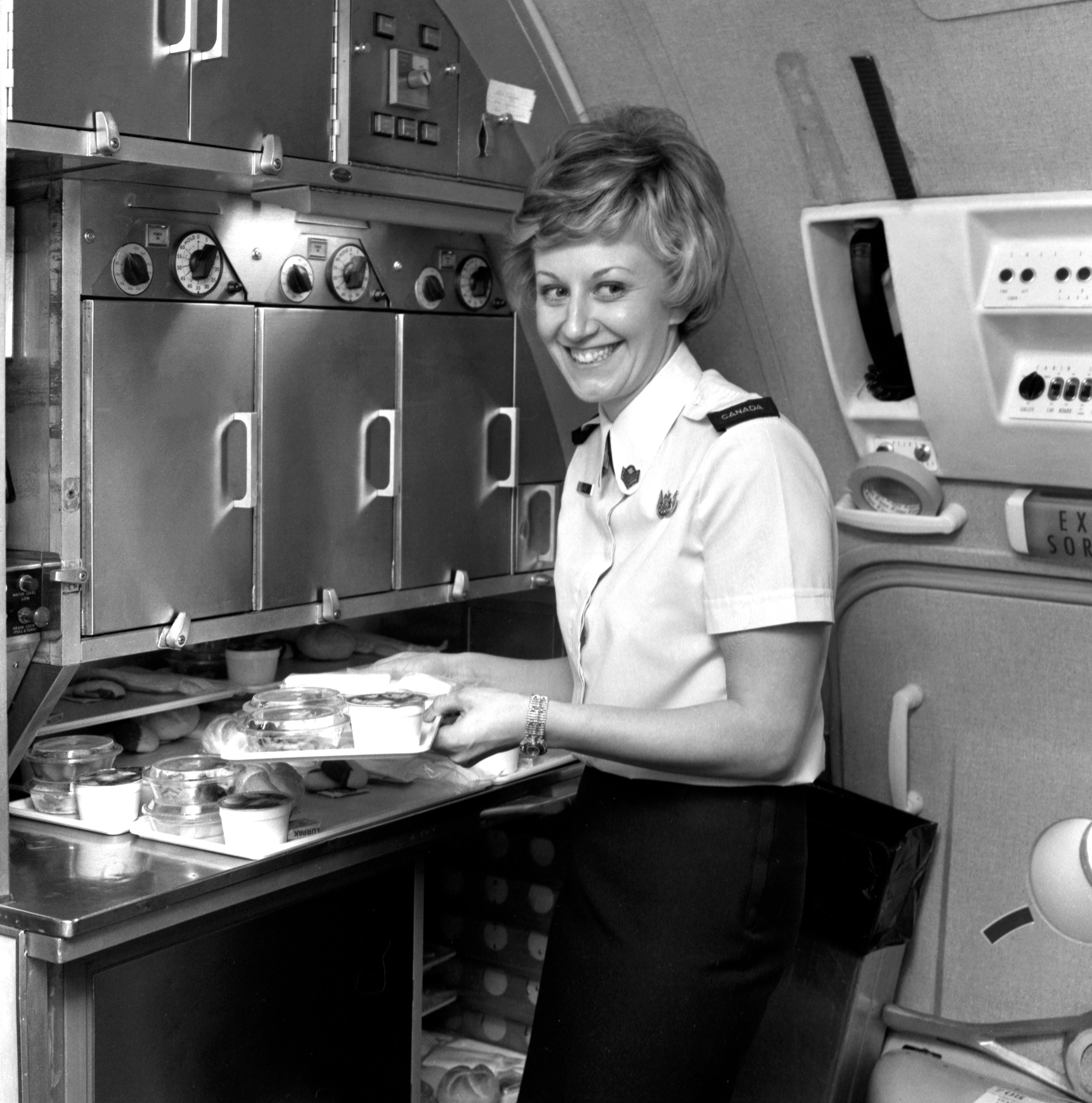 A Canadian Armed Forces stewardess prepares meals for us aboard a Canadian Armed Forces Boeing 707 (CC-137) at Canadian Forces Base Lahr in West Germany,prior to us departing for Canadian Forces base Ottawa in Ontario, Canada.